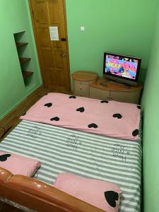 una piccola camera da letto con un letto con lenzuola rosa e un computer di Хостел Центр a Charkiv