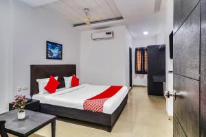 a bedroom with a bed with red pillows and a table at Super Hotel O Qualia Hotel Dilsukhnagar Near Dilsukhnagar Metro Station in Hyderabad
