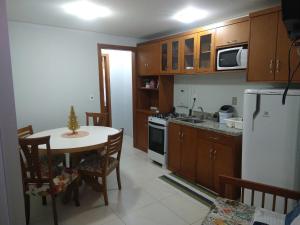 een keuken met een tafel en een witte koelkast bij Apartamento Tomasini in Gramado