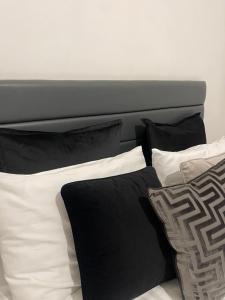 a bed with black and white pillows on it at AptStays in Cardiff