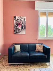 a living room with a black leather couch against a pink wall at Jane's Apartment Rental in Pisa
