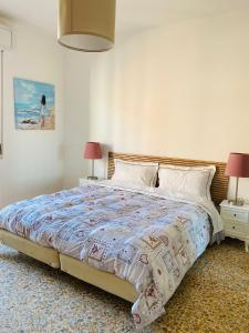 Jane's Apartment Rental في بيزا: غرفة نوم بسرير كبير فيها مصباحين وطاولتين