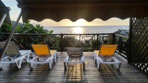 a group of chairs on a deck with the ocean at villa marguerita in Deshaies +7 photos