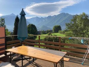 een houten tafel en een parasol op een terras met bergen bij Maison Sottou in Osse-en-Aspe