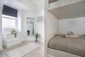 ein weißes Schlafzimmer mit einem Bett und einem Spiegel in der Unterkunft Luxury Apartment - Portobello in Edinburgh