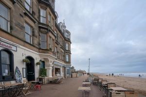 eine Straße mit Tischen und Stühlen am Strand in der Unterkunft Luxury Apartment - Portobello in Edinburgh