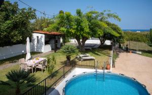 a swimming pool in a yard with a table and chairs at Villa Eleni 100m from the sea in Ropanianá