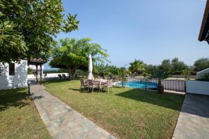 a backyard with a table and chairs and a pool at Villa Eleni 100m from the sea in Ropanianá