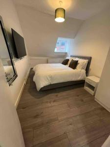 a bedroom with a bed and a wooden floor at The Swan Apartment Ruislip in Ruislip