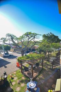 uma vista para um parque com bancos e uma árvore em Pousada Vila da Praia em Pinheira