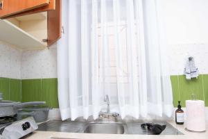 基蘇木的住宿－Tina's 1 BR Apartment with Fast Wi-Fi, Parking and Netflix - Kisumu，厨房配有水槽和带白色窗帘的窗户。