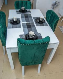 Biały stół z zielonym krzesłem i stół z kapeluszami w obiekcie Tina's 1 BR Apartment with Fast Wi-Fi, Parking and Netflix - Kisumu w mieście Kisumu