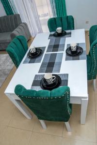 基蘇木的住宿－Tina's 1 BR Apartment with Fast Wi-Fi, Parking and Netflix - Kisumu，白色的餐桌和绿色椅子