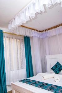 1 dormitorio con 2 camas y cortinas azules y blancas en Tina's 1 BR Apartment with Fast Wi-Fi, Parking and Netflix - Kisumu, en Kisumu
