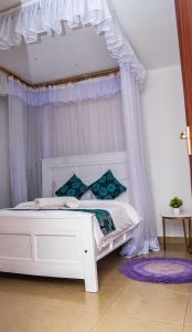 una camera da letto con letto a baldacchino bianco e cuscini blu di Tina's 1 BR Apartment with Fast Wi-Fi, Parking and Netflix - Kisumu a Kisumu