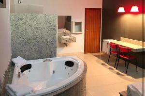 a large bath tub in a bathroom with a table at Motel Queen (Antigo Ícarus) in Lagoa Santa