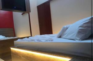 1 cama con sábanas blancas y almohadas en una habitación en Motel Queen (Antigo Ícarus), en Lagoa Santa