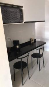 uma cozinha com um balcão preto e dois bancos em Completo com Ar-condicionado no Recife