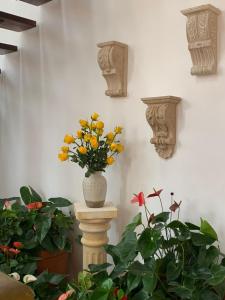 a vase of flowers on a pillar in a room with plants at Santa Lucía Casa Hotel in Villa de Leyva