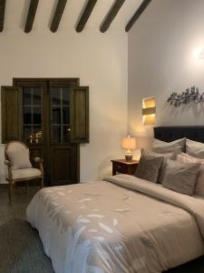 1 dormitorio con 1 cama grande y 1 silla en Santa Lucía Casa Hotel, en Villa de Leyva