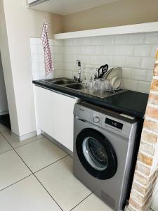 a kitchen with a washing machine and a sink at ModernLuxe Apartment in Windhoek