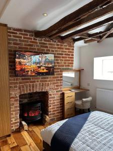 een slaapkamer met een bakstenen muur, een bed en een open haard bij The Signature 1360’s - Modern Apartment in Barnet