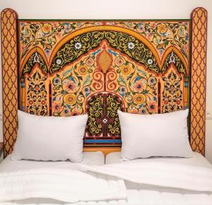 Bett mit farbenfrohem Kopfteil und 2 Kissen in der Unterkunft Dar Al Mardi Fes in Fès