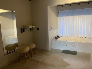 a bathroom with stools and a tub with a window at Portal Dos Campos in Ponta Grossa