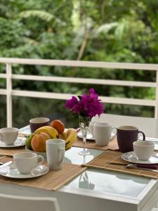 una mesa con tazas y platos de comida y flores en Appartement Coeur de Papillon, en Baie-Mahault