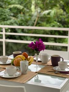 a table with cups and plates of food and flowers at Appartement Coeur de Papillon in Baie-Mahault