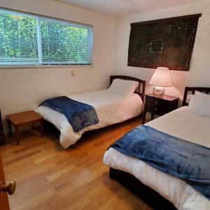 a bedroom with two beds and a lamp and a window at Sweet 2 bedroom close to U of Oregon & track! in Eugene