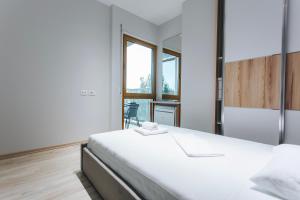 a white bedroom with a bed and a window at The Heart of Tirana in Tirana