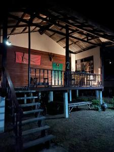 una casa con porche de madera y escaleras en la parte delantera en Lek's Issan Home and Travel, en Ban Kut Khaen