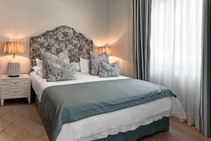 Un dormitorio con una cama grande y una ventana en The Coach House, en Franschhoek