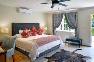 1 dormitorio con 1 cama con almohadas rojas y ventilador de techo en The Coach House, en Franschhoek