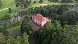 a house with a red roof in the middle of trees at Quartos privados - Quinta da Paz in Santa Cruz