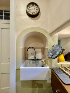 a clock on the wall above a white bath tub at Quartos privados - Quinta da Paz in Santa Cruz