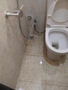 uma casa de banho com um WC com uma mangueira ao lado em B8B Chessville Corte 3 em Abuja
