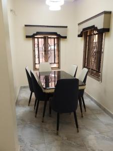 uma sala de jantar com uma mesa de vidro e cadeiras em B8B Chessville Corte 3 em Abuja