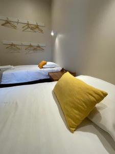 a bedroom with two beds and a yellow pillow at Quartos privados - Quinta da Paz in Santa Cruz