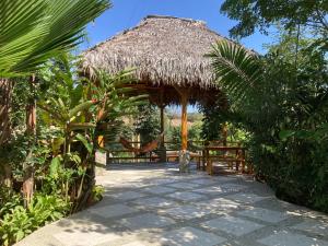 einen Pavillon mit einem Strohschirm und einer Bank in der Unterkunft Hotel La Costa International in Puerto López