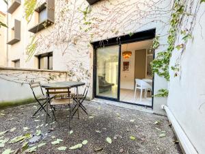 a patio with a table and chairs in front of a building at Suite Cumba in Villeurbanne