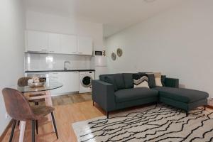 ein Wohnzimmer mit einem Sofa und einem Tisch sowie eine Küche in der Unterkunft Modern studio near Metro Station in Senhora da Hora