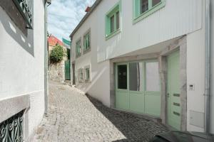 alejka z zielonymi drzwiami garażowymi na białym budynku w obiekcie Mint Flat in Foz by the Douro w Porto
