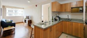 a kitchen with a counter top and a living room at Moderno y acogedor cerca al mar in Lima