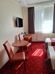 Habitación de hotel con cama, mesa y sillas en Pensjonat Trzy Stawy, en Jelcz