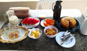 einem Tisch mit Teller mit Lebensmitteln und einem Krug Milch in der Unterkunft chalé caminho da mata in Cavalcante
