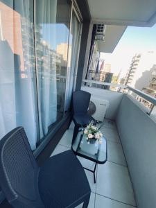a balcony with two chairs and a table with flowers on it at Cálido Apart en el corazón de Buenos Aires con piscina in Buenos Aires