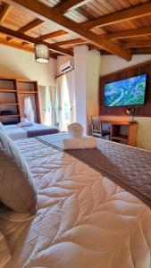 een groot bed in een kamer met een tv aan de muur bij Valle Paradiso in Praia do Rosa