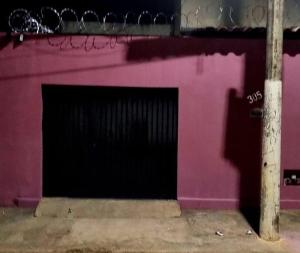 a pink wall with a black gate on a building at casa com, ar condicionado e suíte no major prates in Montes Claros